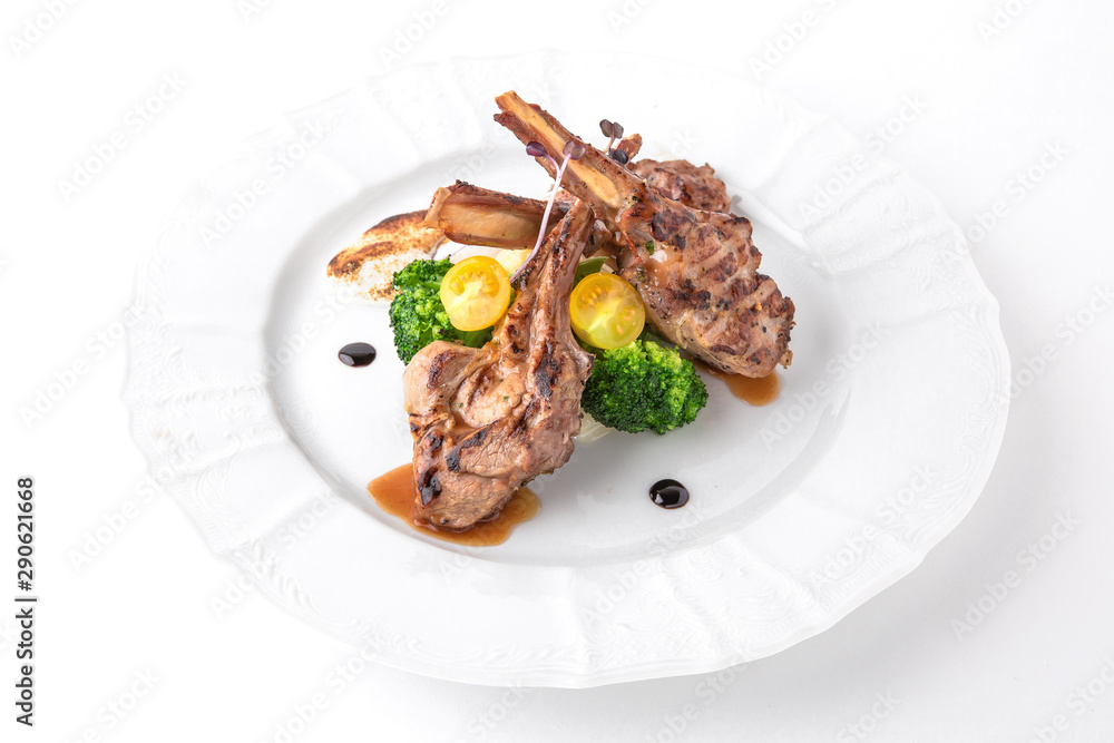 Grilled tender lamb ribs in sauce with vegetables, berries and greens. Banquet festive dishes. Fine dining restaurant menu. White background.
