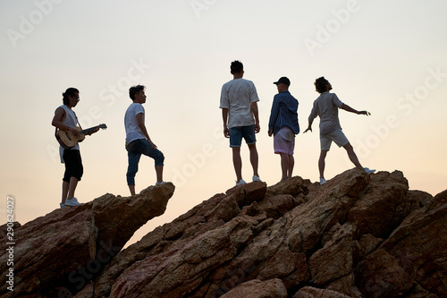 group of rocker standing on top of rocks singing