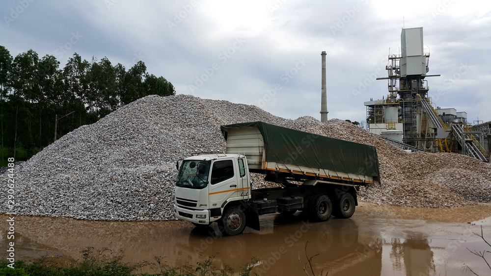 Fototapeta premium Truck and Large piles of limestone for use in lime kiln line with blue sky and cloud . Limestone gravel background Texture.