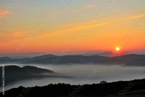 sunset over mountains with fog in the valleys