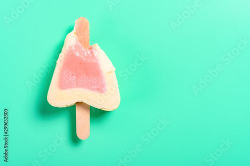 top view strawberry flavor popsicle with some bites on a green background