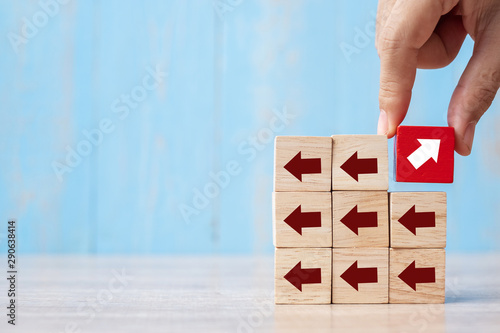 Businessman hand placing or pulling Red block with different direction of arrow on table background. Business Growth, Improvement, strategy, Successful, different and Unique Concepts © Jo Panuwat D