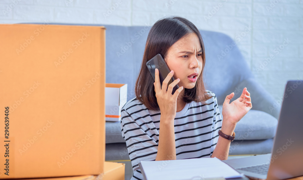 Startup small business concept, young Asian woman owner talking on the smartphone with customers about ordering products, Seller prepares the delivery box. Startup small business concept, young Asian woman owner talking on the smartphone with customers about ordering products, Seller prepares the delivery box.