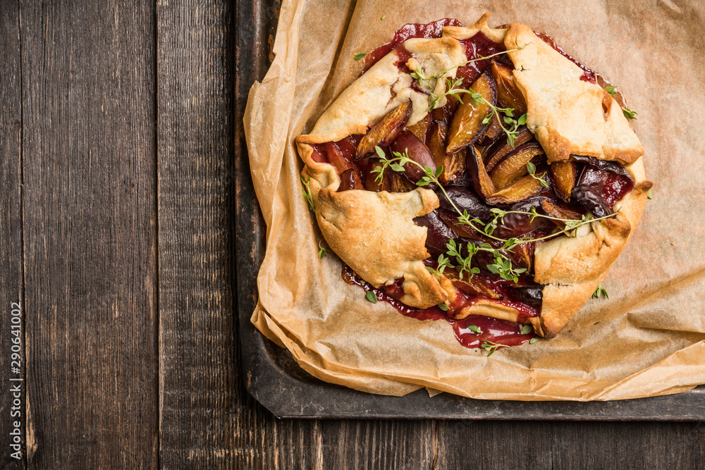 Freshly baked tart with plums and thyme on the rustic background. Selective focus. Shallow depth of field. Freshly baked tart with plums and thyme on the rustic background. Selective focus. Shallow depth of field.