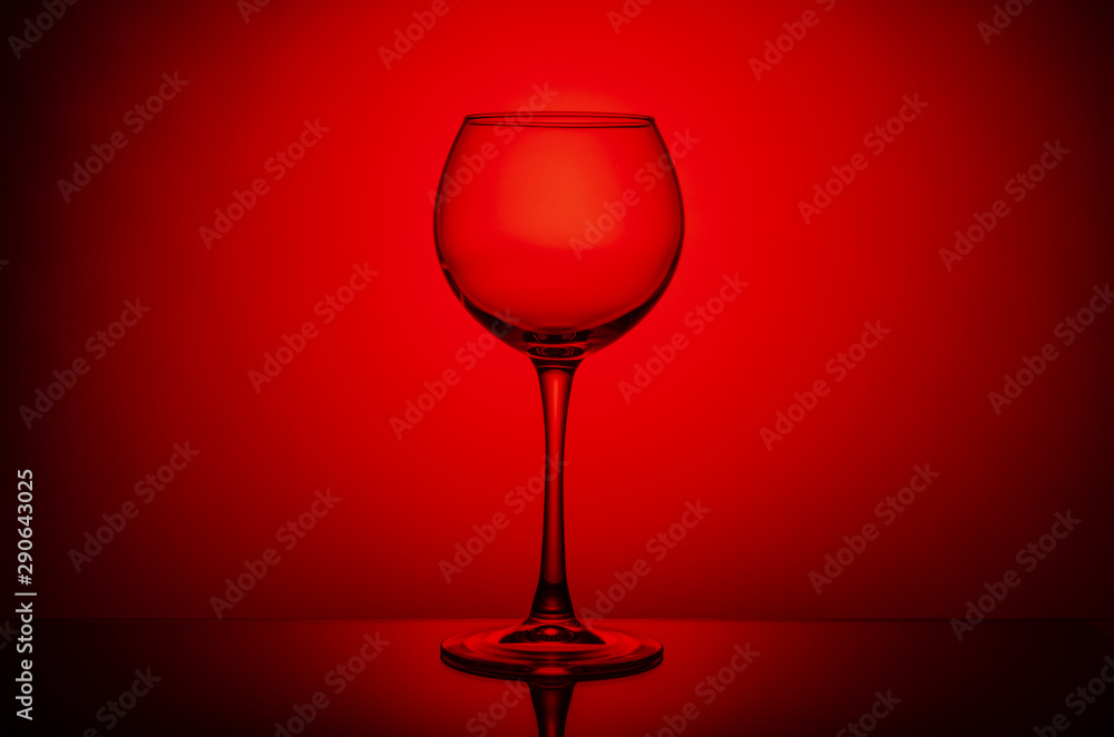 Wine glass with a drink on a red light background Wine glass with a drink on a red light background