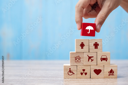 Hand holding umbrella wood block cover Insurance icon. healthcare medical, life, car, home, travel insurance concept photo