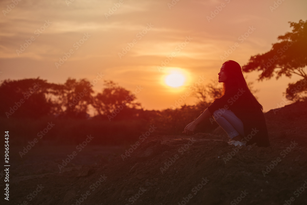 Portrait of lonely women sitting and thinking something over sunset background silhouette style. Lonely and depression concept.