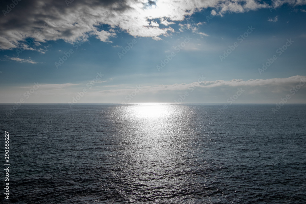 Sun shinning over the sea’s horizon on partially sunny day in England, UK.