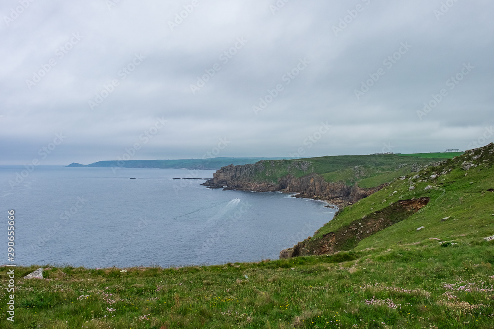 Grassy and rocky cliff overlooking the sea on a cloudy day in England, UK.