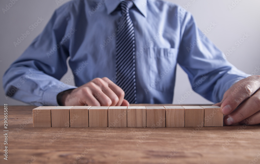 Businessman holding wooden cube on a wooden table. Businessman holding wooden cube on a wooden table.