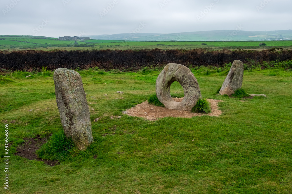 A unique rock structure that looks like the numbers 101 overlooks the green English countryside on this cloudy day.