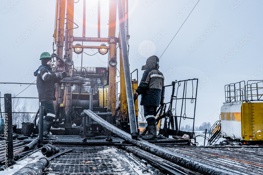 Naklejka premium Offshore oil rig worker prepare tool and equipment for perforation oil and gas well at wellhead platform. Making up a drill pipe connection. A view for drill pipe connection from between the stands
