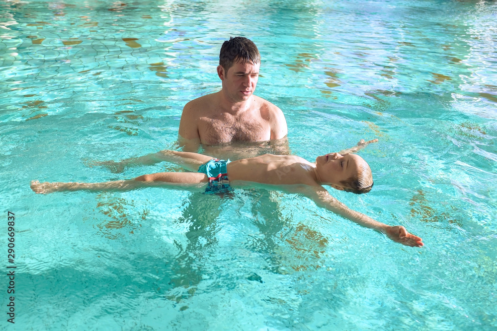 Happy father and son swimming lesson in the pool. Child learning