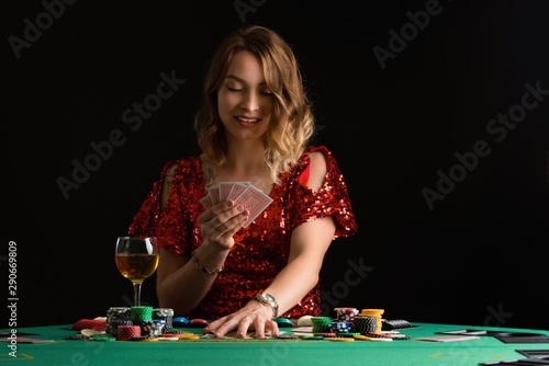A young girl in a red evening dress plays poker in a casino. on a black background with space for design