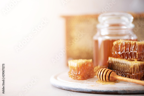 Bee pollen granules, honey jar with wooden dropper, honeycomb on grey backdrop. Copy space. Autumn harvest concept