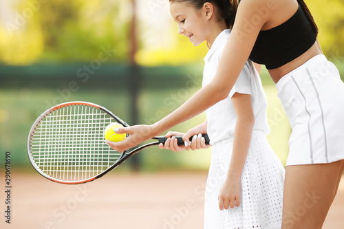 Little girl and her mother playing tennis on court © Pixel-Shot