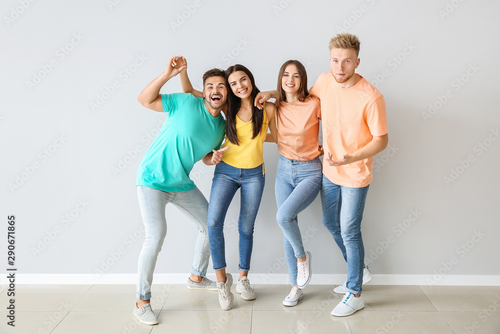 Group of young people in stylish casual clothes near light wall