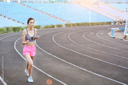 Sporty Asian woman running at the stadium