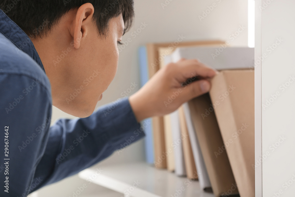 Fototapeta premium Man Selecting Book from Bookshelf