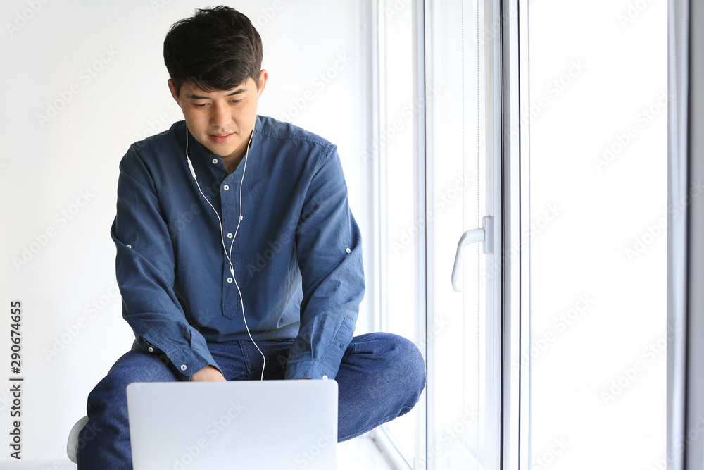 Asian student with laptop preparing for exam near window Asian student with laptop preparing for exam near window