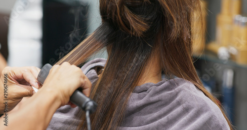 Woman having hair straightening treatment in hair salon photo