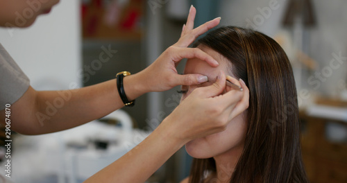 Make up artist shaping eyebrow on female model at studio
