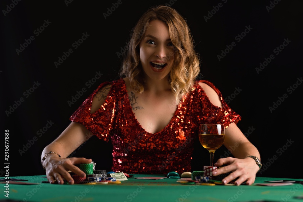 The girl plays poker in a casino and wins and takes all the chips. Card game, casino background. Victory and success. The girl plays poker in a casino and wins and takes all the chips. Card game, casino background. Victory and success.