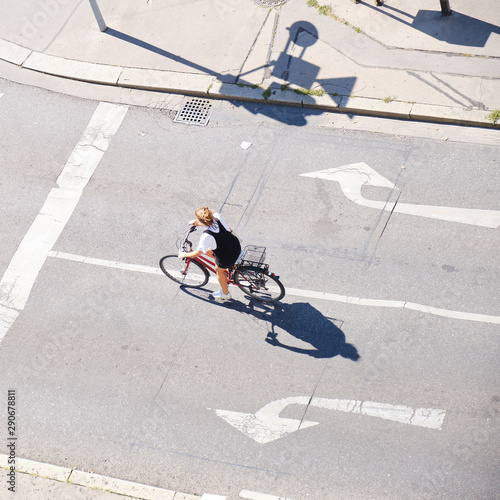 Obraz na płótnie Unrecognizable woman on a bicycle, between left and right arrow signs - view from above with long shadows. w salonie