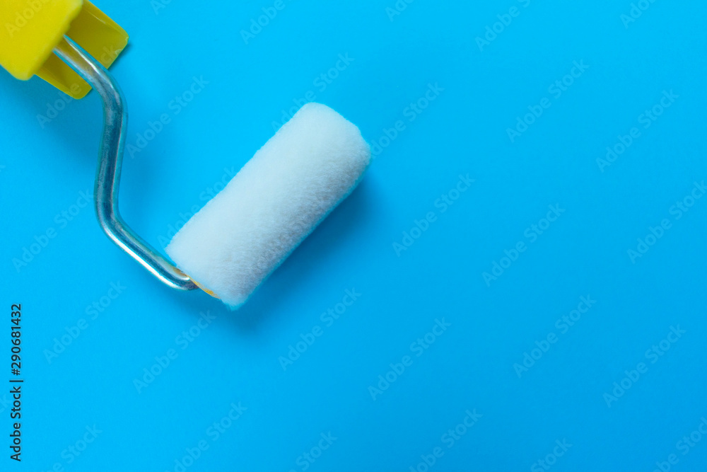 Obraz premium Paint roller isolated on blue background. Copy space.