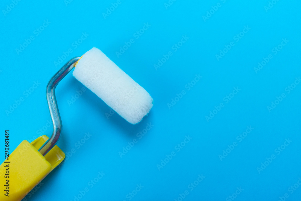 Obraz premium Paint roller isolated on blue background. Copy space.