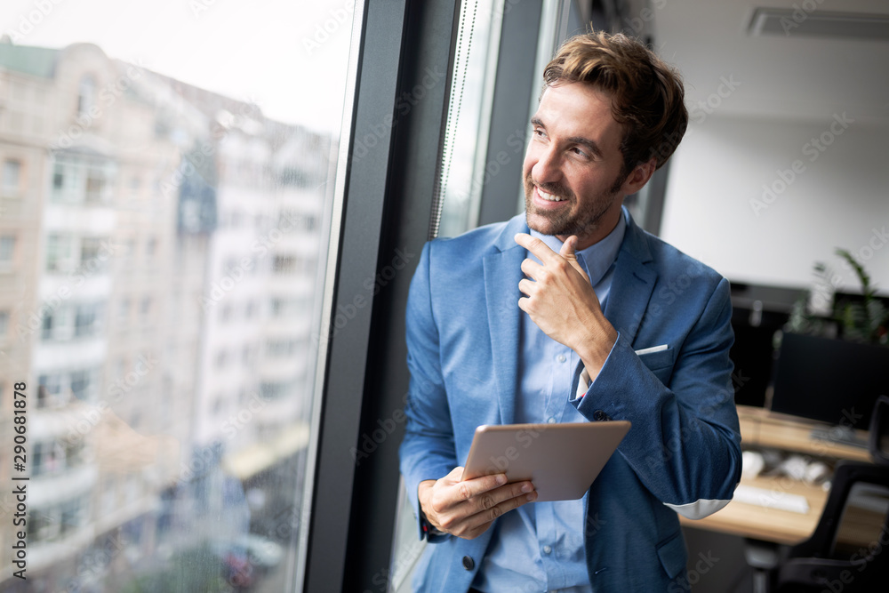 © NDABCREATIVITY - Portrait of confident young businessman using digital tablet