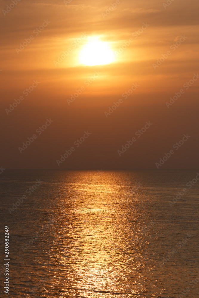 Golden color sunset on sea. Landscape with sun and dusk light sky with sun reflection on water surface.