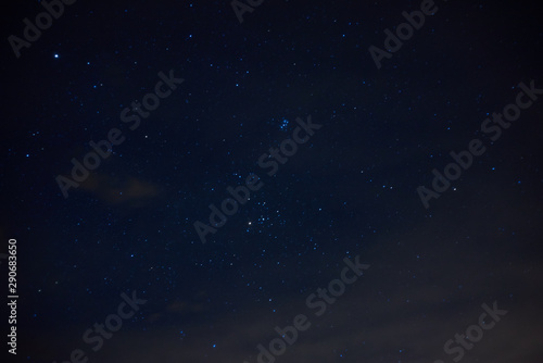 Night starry sky. Bright stars and constellations are visible through light clouds.