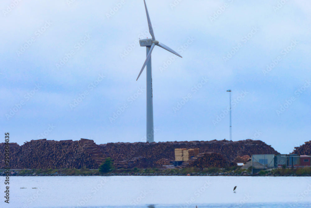 Klintehamn, Gotland, Sweden A wind turbine stands above a stack of wood in the harbor.