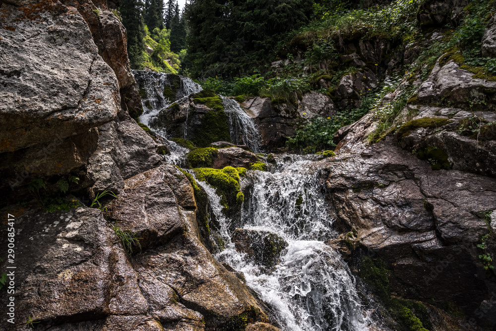 A fast mountain river flows through wet stones in the mountains