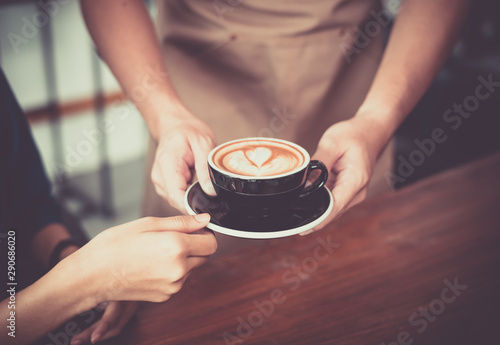 Barista hold coffee cup serving a client at the coffee shop.