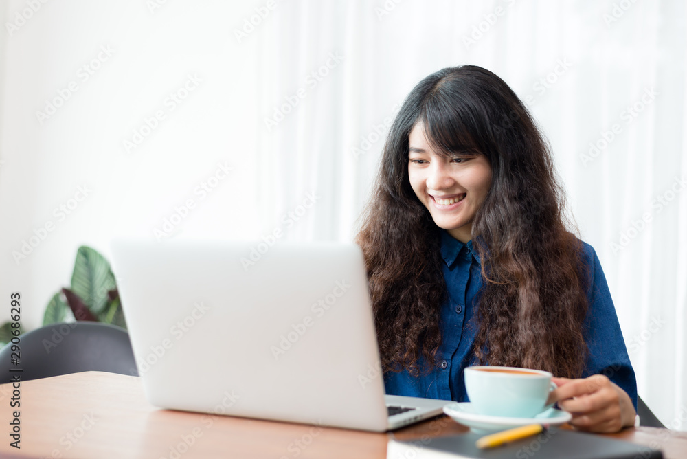 Young woman or student using laptop sitting at coffee shop. Happy girl working online or studying and using notebook. Freelance business concept. Young woman or student using laptop sitting at coffee shop. Happy girl working online or studying and using notebook. Freelance business concept.