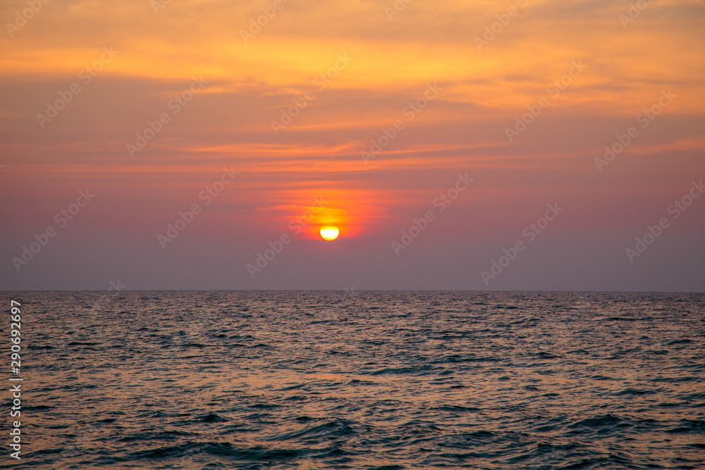 Fototapeta premium sunset on the sea. sandy beach, clear water, waves. surf line in the warm colors of the setting sun.