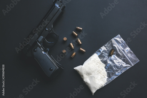 Gun with bullets lying on the table. Criminal problems. Drugs in the packet. Illegal selling. photo
