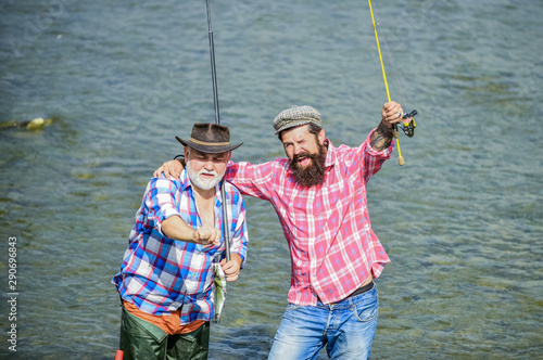 Male friendship. Father and son fishing. Summer weekend. Fishing together. Men stand in water. Nice catch concept. Fishing team. Happy fisherman with fishing rod and net. Hobby and sport activity