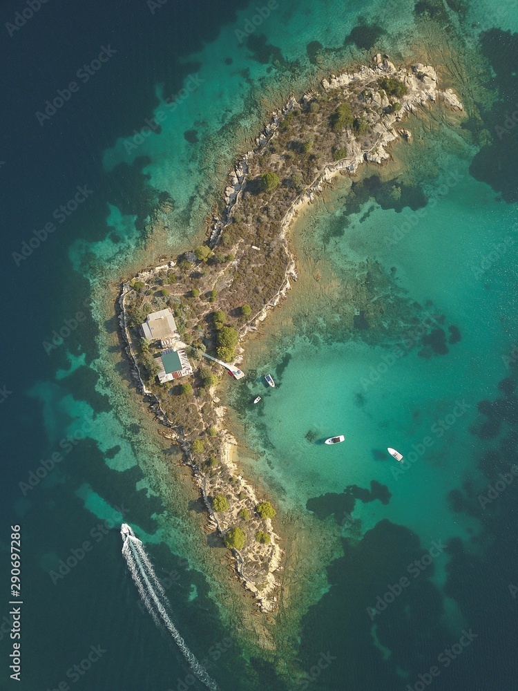 Halkidiki, Greece : boats and yachts moored near the private island  in a secluded location on the Aegean sea. View from drone
