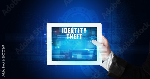 Wallpaper Mural Young business person working on tablet and shows the digital sign: IDENTITY THEFT Torontodigital.ca