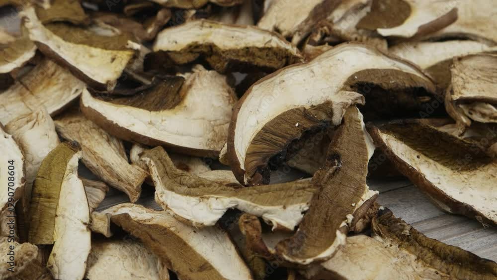 A pile of slices of dried porcini mushrooms on a dark wooden table, background A pile of slices of dried porcini mushrooms on a dark wooden table, background
