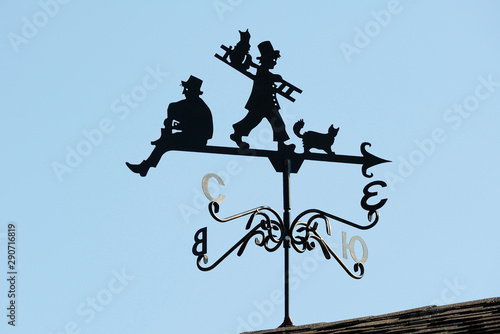 Weathervane in the form of people and cats.. A product made of metal on the roof of the house.