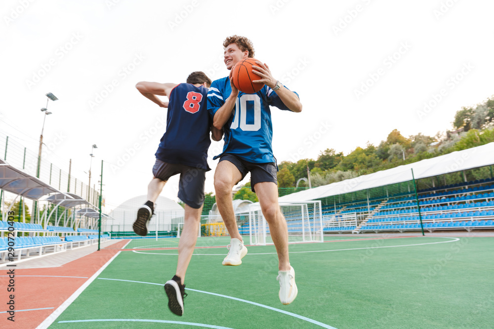 Two confident fit sportsmen playing basketball