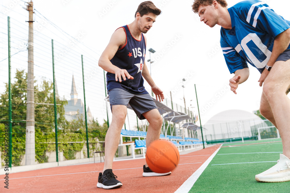 Two confident fit sportsmen playing basketball