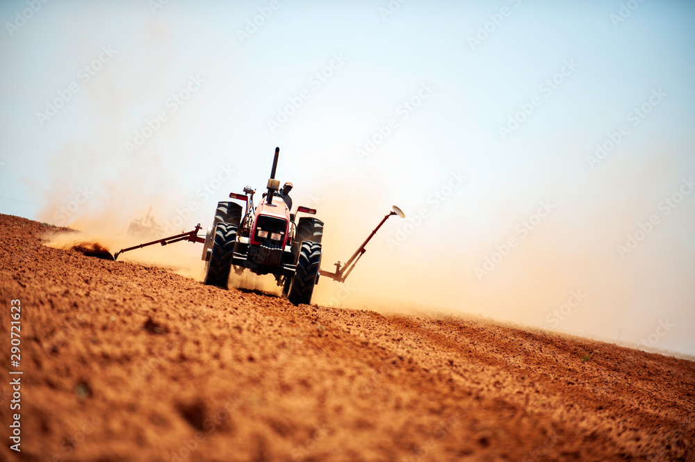 Fototapeta premium Hot heat summer sun ploughing fields in Kwazulu Natal South Africa, dusty movement blur, tractors, machinery