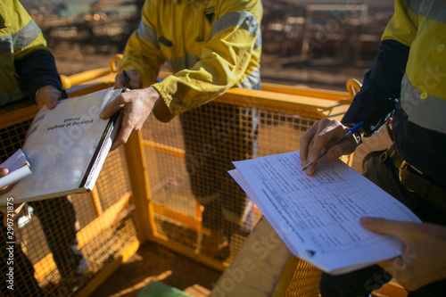 Miner supervisor checking reviewing document before issued sigh of working at height permit JSA risk assessment on site prior to performing high risk work on construction mine site, Perth, Australia  photo