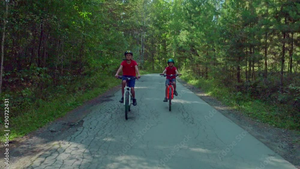 Young boys in helmet riding bicycles on the road in the park. Young boys in helmet riding bicycles on the road in the park.