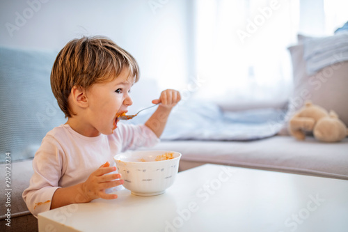 Cute child eating healthy food with with the left hand at home. Cute child little boy eats healthy food vegetables. It's really yummy. Kid eating healthy food at home or kindergarten